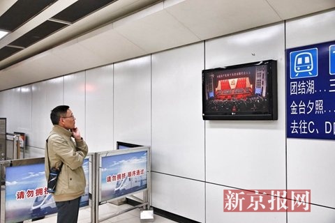 市民在地铁十号线农业展览馆站观看开幕式直播。